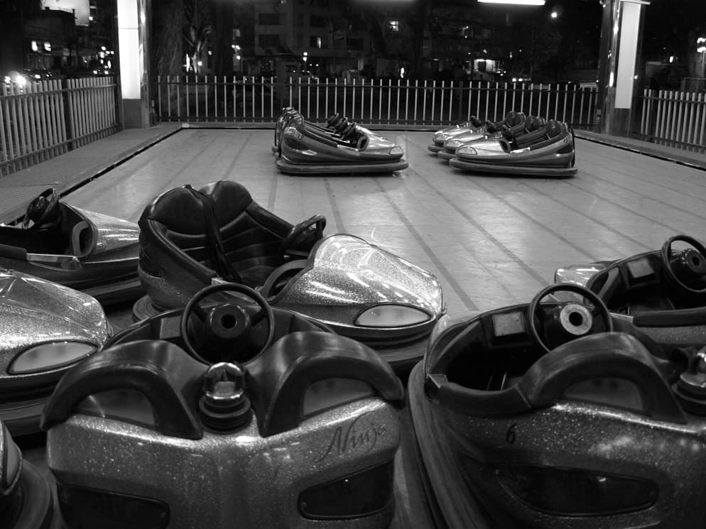 Empty bumper cars resting on the track of a fairground at night
