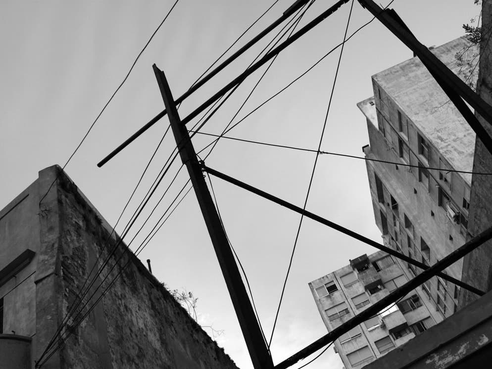 Utility poles and cables criss-crossing between old apartment buildings