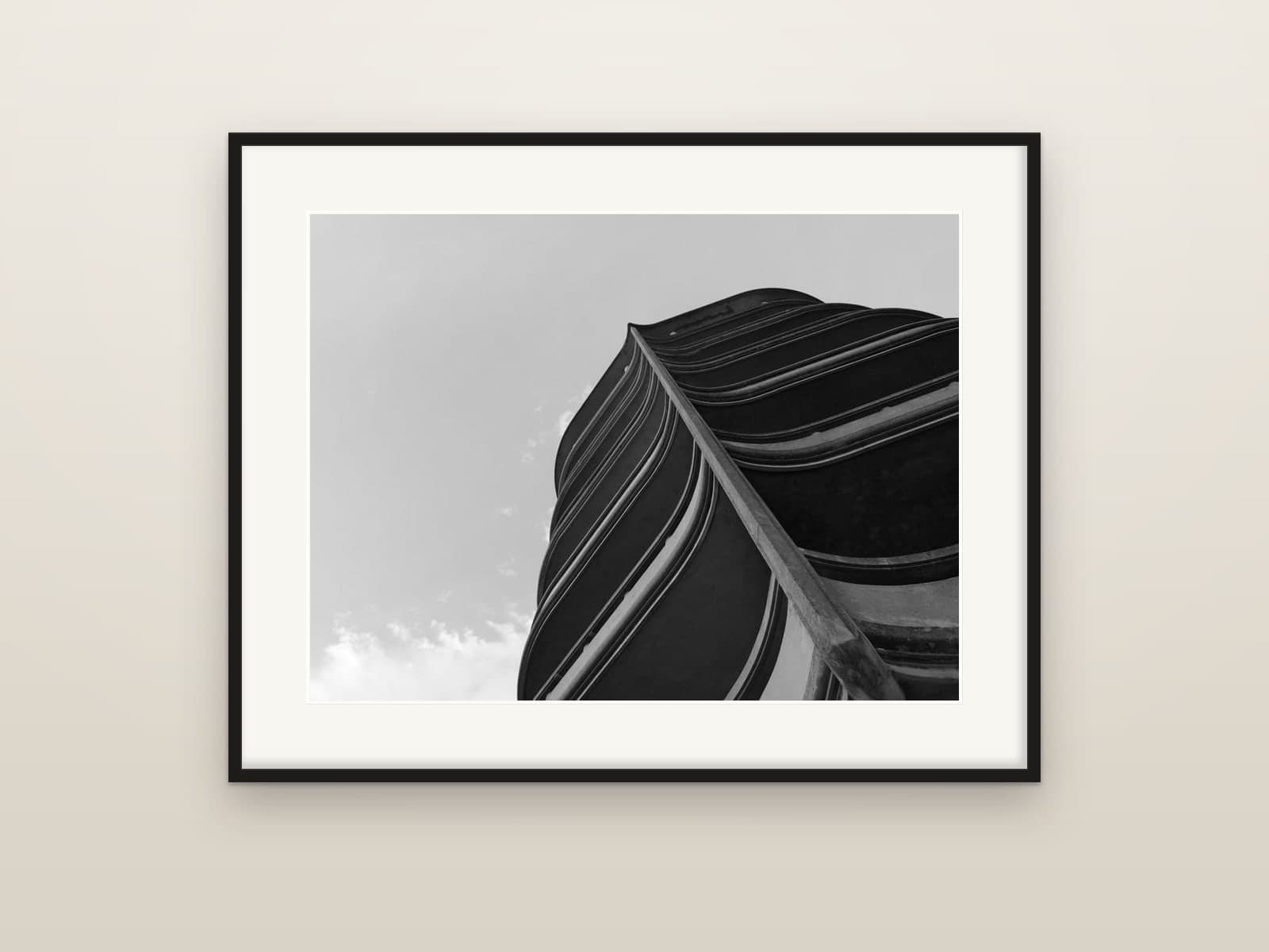 The curving balconies of a modernist tower seen from below, shown as a framed print