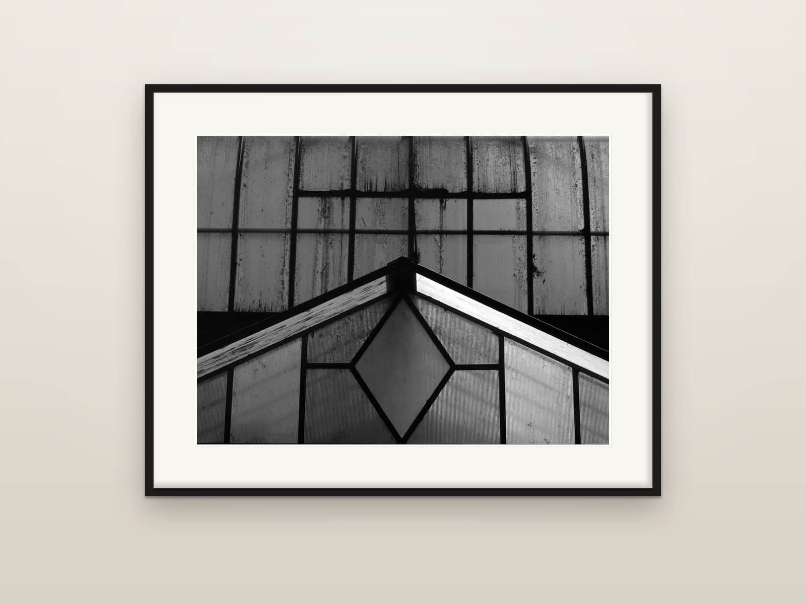 Geometric panes and the pitched roof of an old glasshouse, shown as a framed print