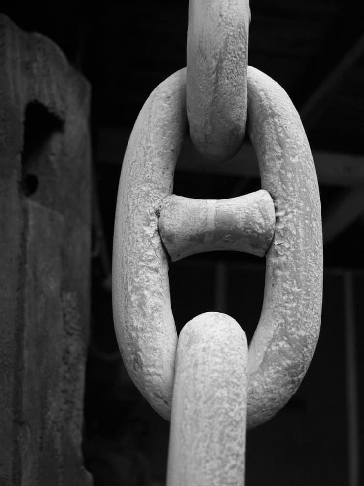 A heavy, weathered chain link hanging in a dark warehouse