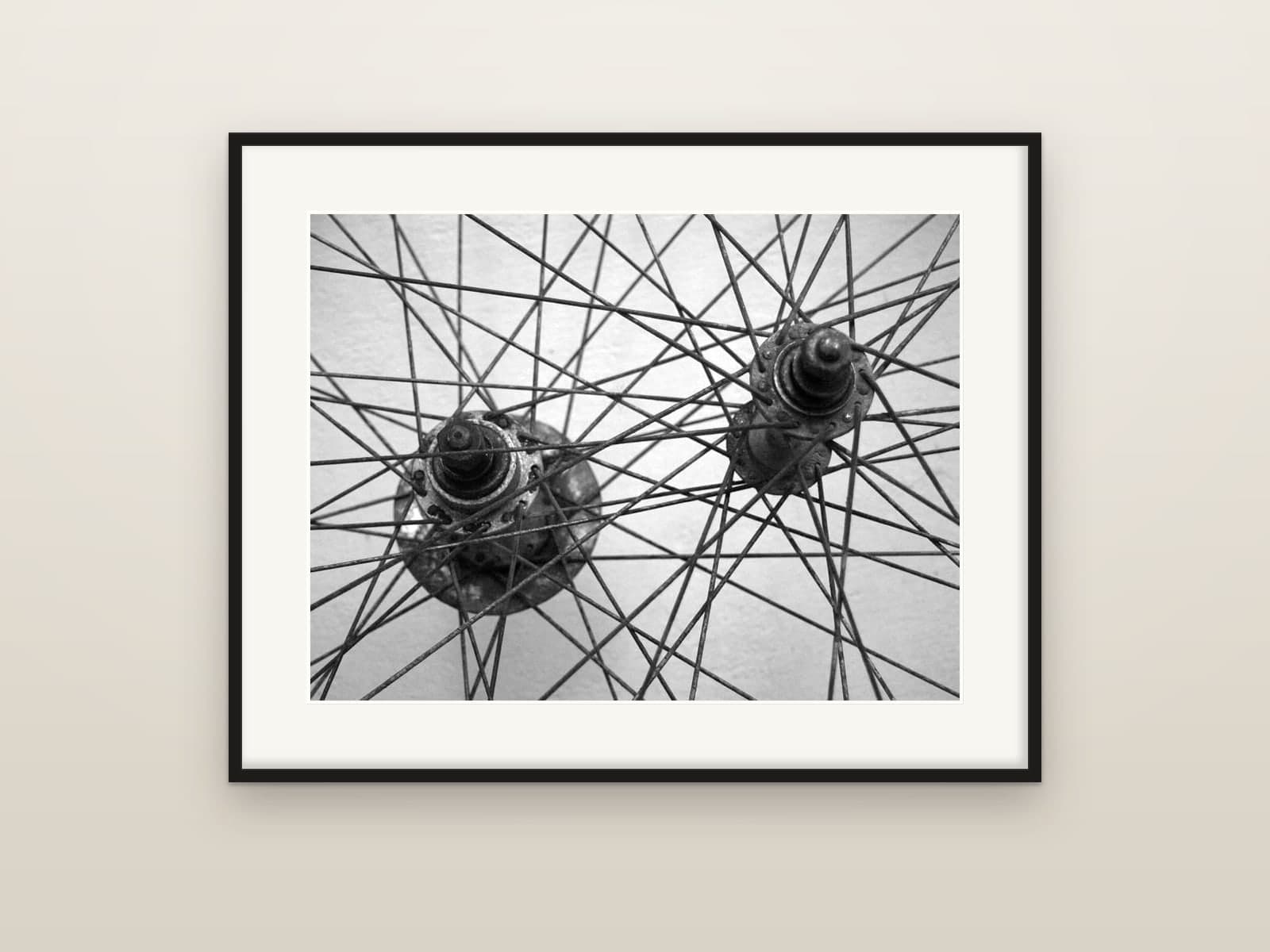 The overlapping spokes and hubs of two bicycle wheels, shown as a framed print